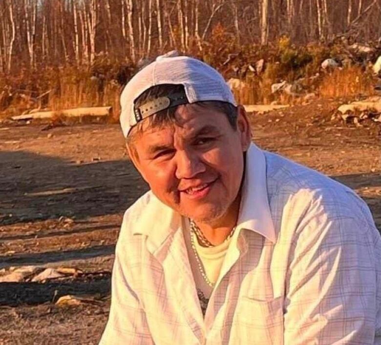 An Indigenous man in his early 40s smiles in the sun surrounded by the forest.