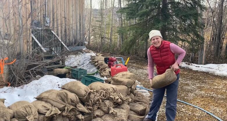 Woman holding placing a sandbag on a pile of sandbags outside of her house.