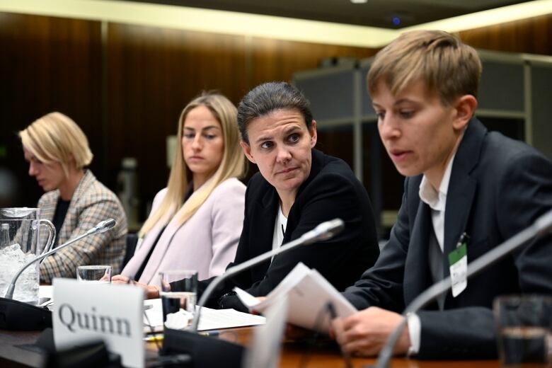 Four people speak at a committee meeting.