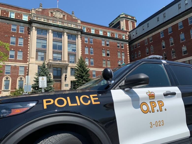 A close-up of a police car with a brown brick building in the background.