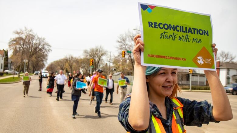 A woman holds a sign over her head that says 