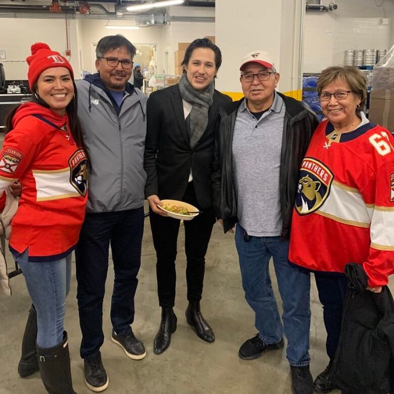 A family in Panthers jerseys stands with a young man in a suit jacket. 