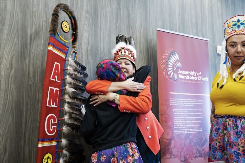 Two women embrace. 