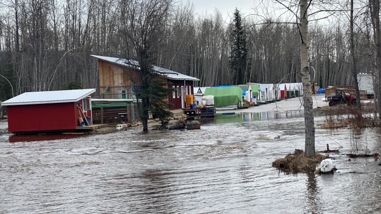 A row of buildings and tents are seen amid floodwaters.