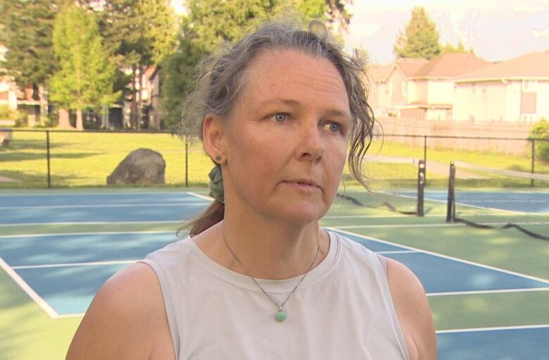 A woman stands on a pickleball court