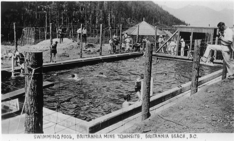 A black and white photo of children swimming in a pool.