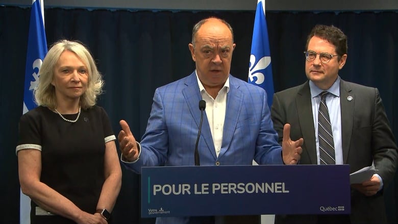 Three people stand behind a podium