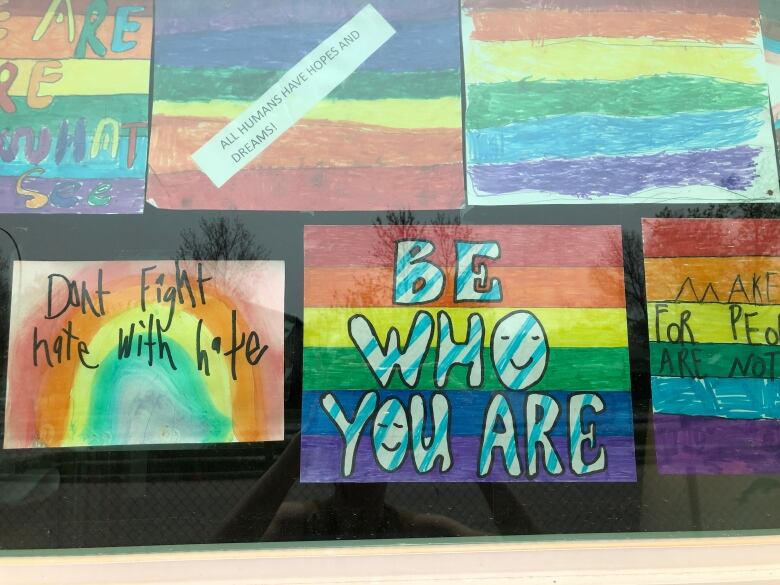 Several rainbow-coloured pieces of paper are posted to a window. 