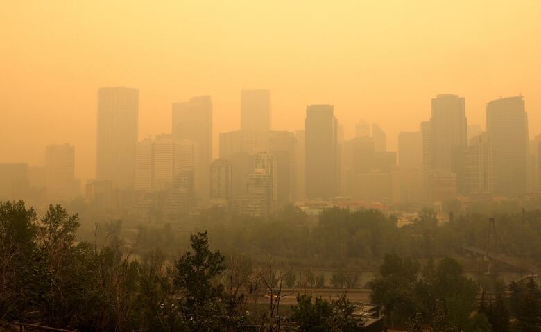 Orange haze blankets Calgary city skyline due to Alberta wildfires.