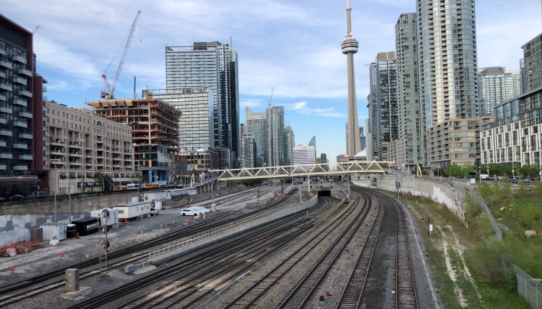 A view overlooking railway lines in the foreground with the CN Tower and downtown Toronto in the background.   