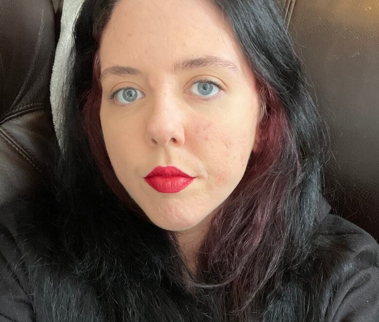 A selfie of a woman with long dark hair wearing red lipstick