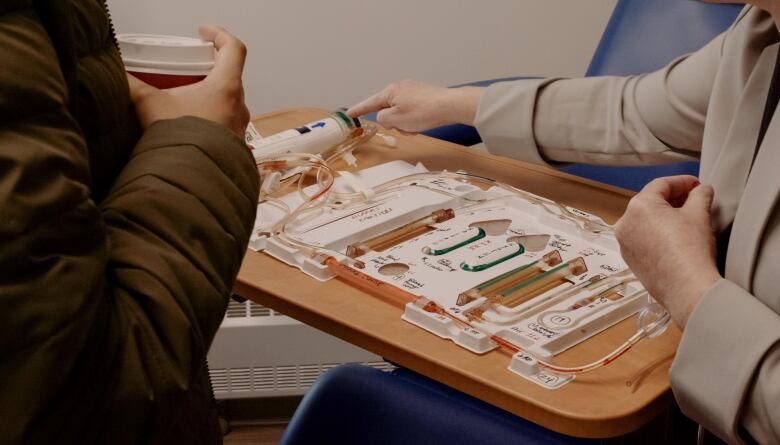 A woman points to a tray of equipment for homedialysis