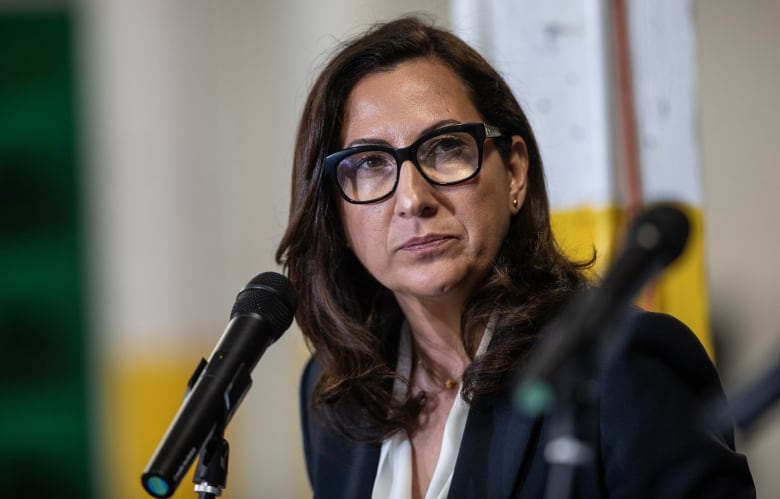 A woman with glasses in front of a microphone during a debate