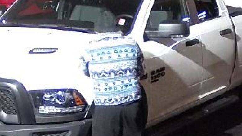 A suspect in front of a white Dodge Ram truck.