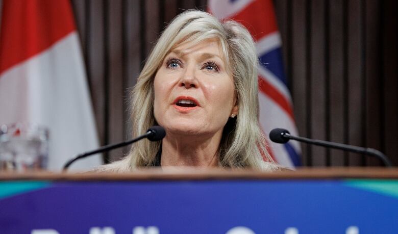 A woman behind a podium, seen in a close up shot.