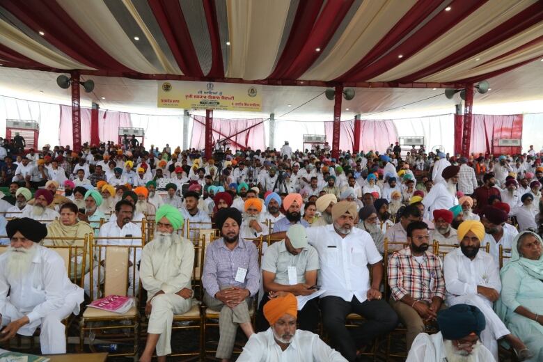 Hundreds of farmers are pictured in a tented area.