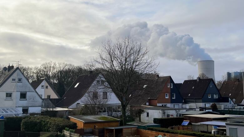 A row of houses with a smokestack in the background. 