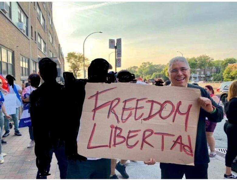 A man is seen protecting with a sign outside of the Cuban consulate in Montreal.