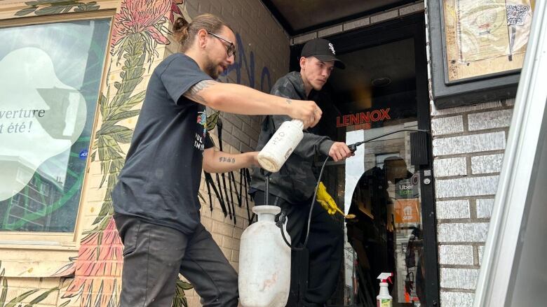 two men cleaning graffiti off a wall