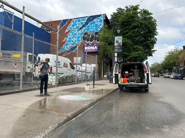 man using a pressure washer to clean graffiti