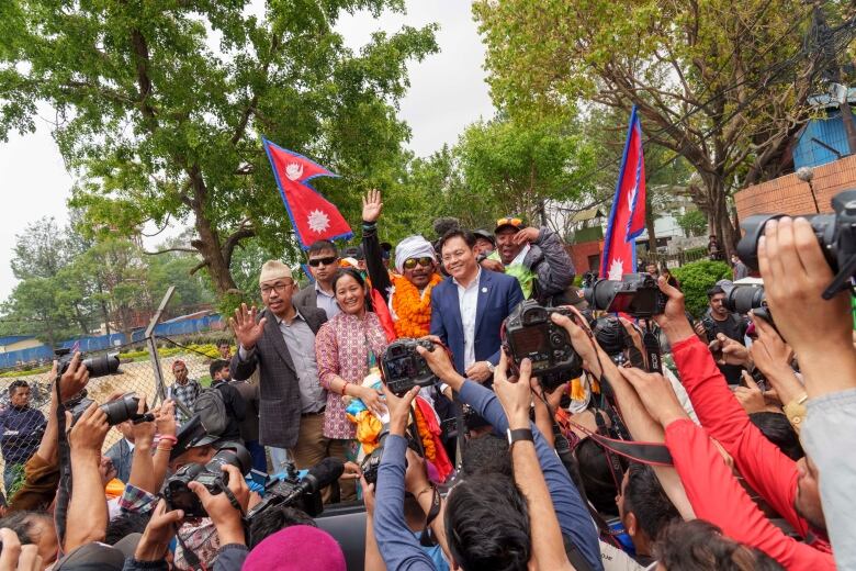 A man is surrounded by a group of people holding cameras.