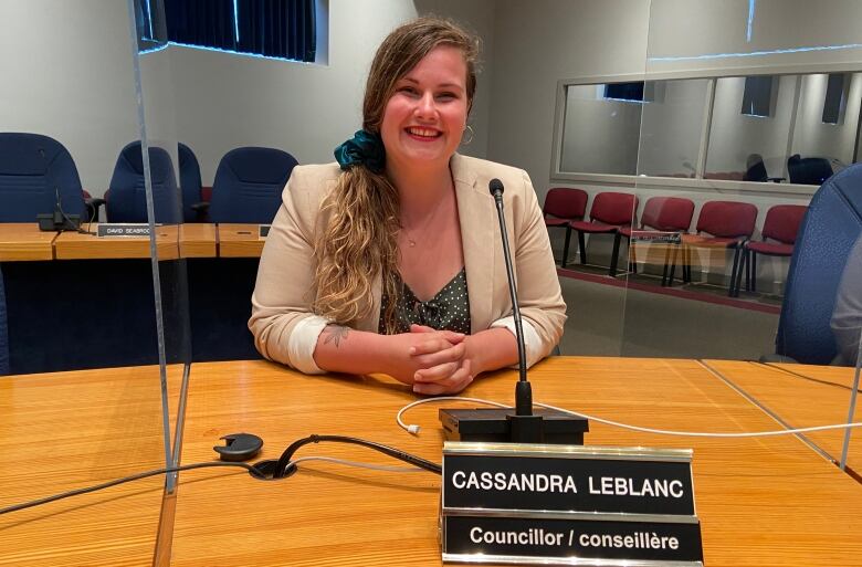 A woman sits in front of a microphone inside Fredericton council chambers.