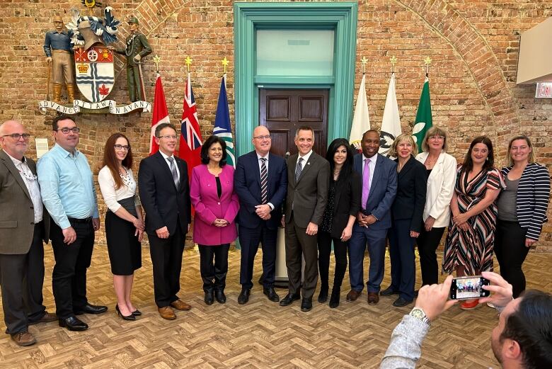 A group of smiling people pose for a photo in front of flags.