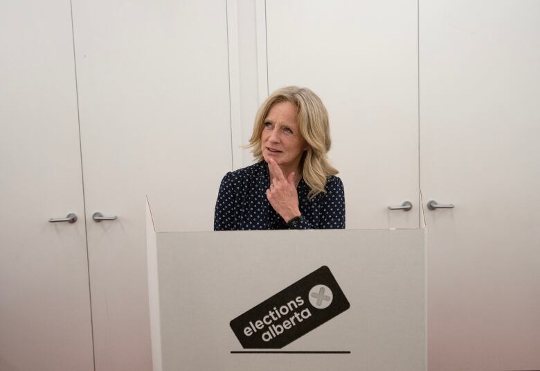 As she stands at a voting station, a politician cheekily puts her finger to her chin, as though she's mulling how to vote.