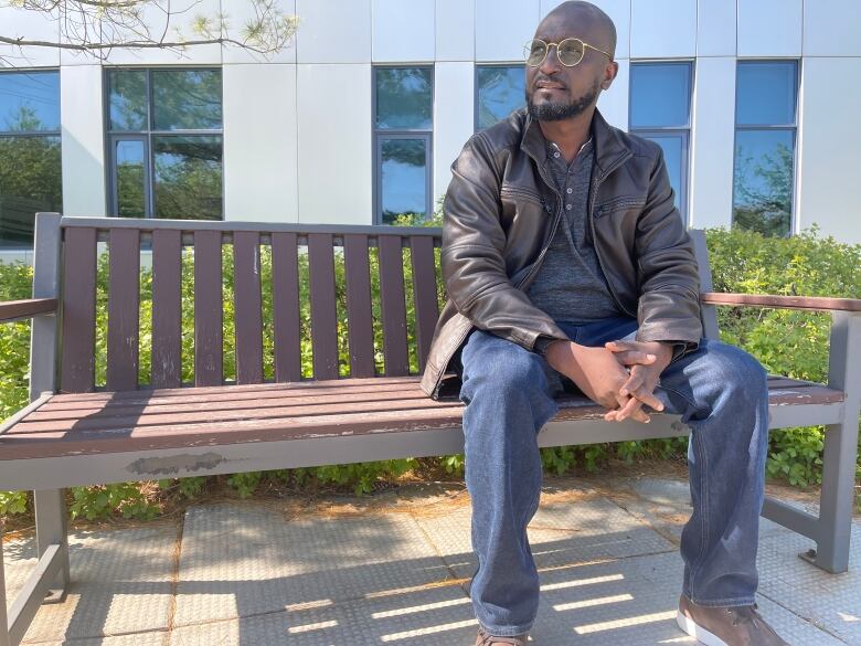 A man sits on a bench on a sunny spring day.