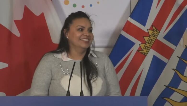 Vancouver resident Carla Lopez, who came to B.C. as a refugee from Mexico with her spouse and two children, stands in front of a Canadian and B.C. flag as she speaks at a provincial announcement on May 24 that increased funding for newcomer settlement services.