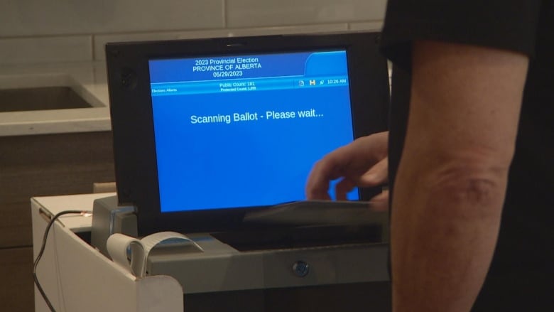 A voter enters his paper ballot into a tabulator machine at an advanced polling station in Sherwood Park on Tuesday. 