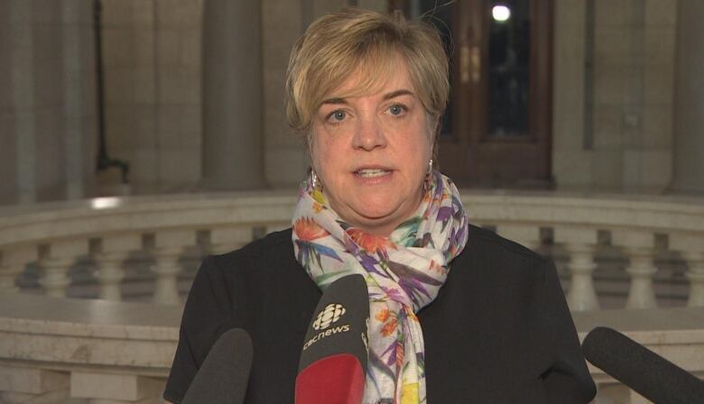 A woman is shown speaking to the press.