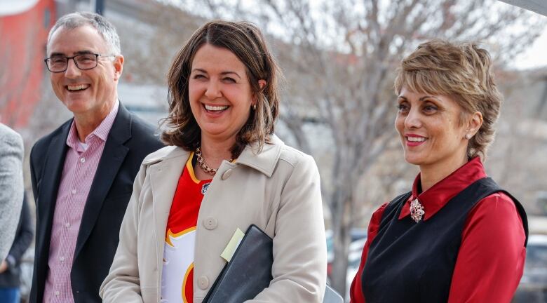 Two women and a man smile.