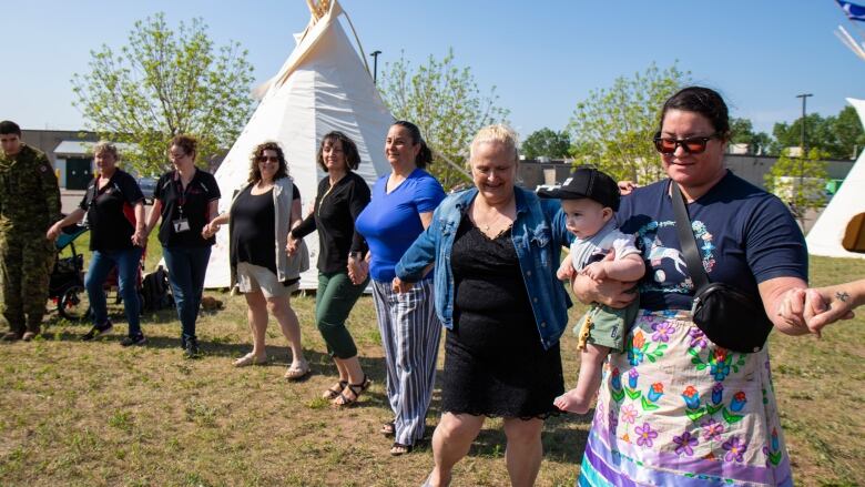 People hold hands and dance in a circle during a round dance.