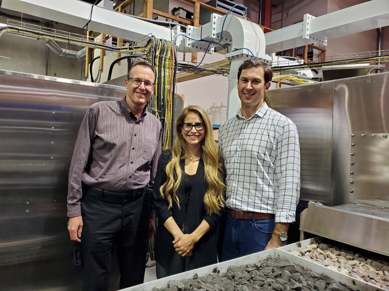 A group of three people in front of hydrogen tanks