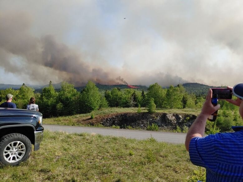 People looking at fire and dark smoke in the distance