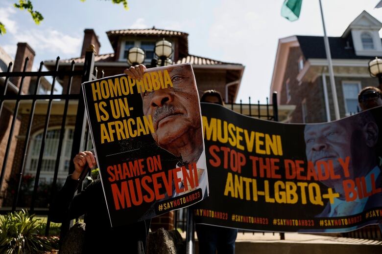 Several signs are shown, carried by demonstrators in front of a building.