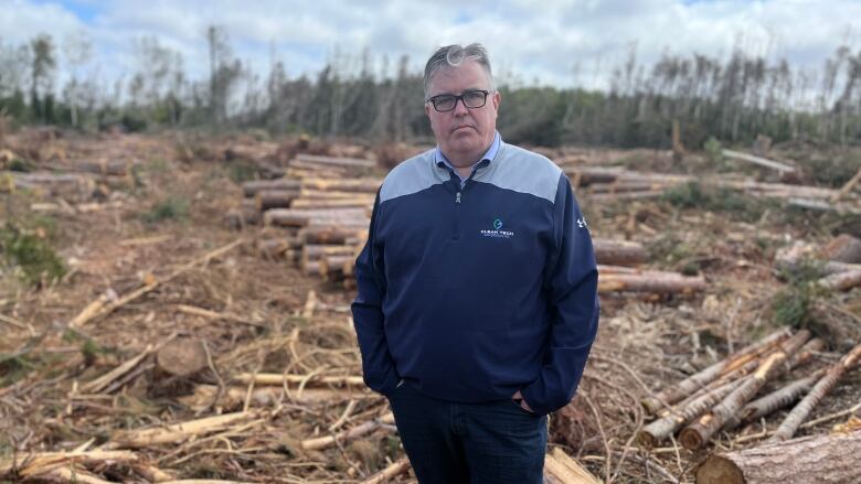 Environment Minister Steven Myers standing in field with downed trees.