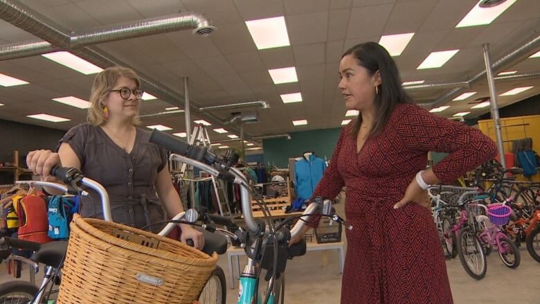 Two women stand beside each other in a bike rental store.