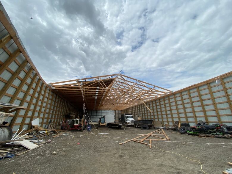 A metal shed with wood base is missing most of its roof 