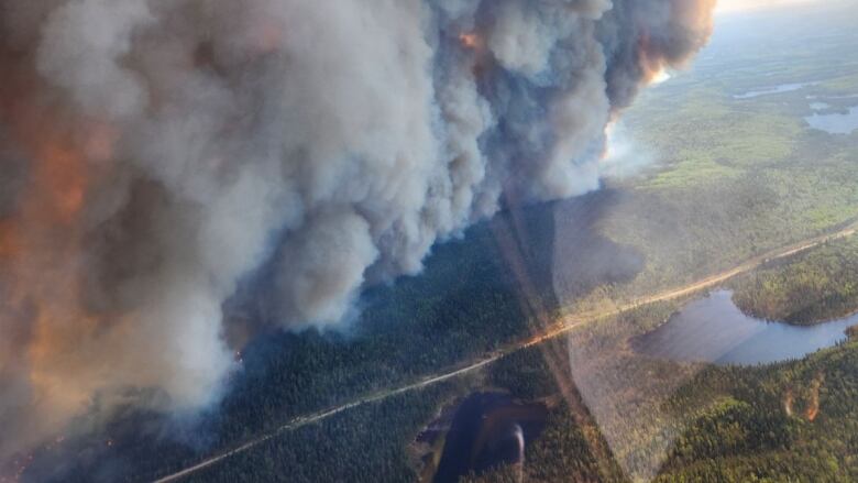 An aerial photo show black and orange smoke over a section of forested northwestern Ontario.