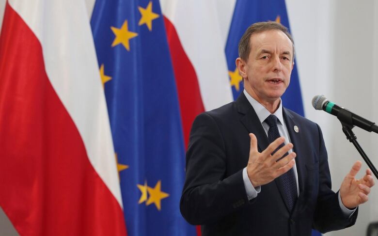 Man stands in front of a flag at a podium.