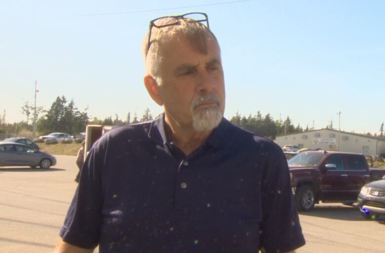 A man in a short-sleeved shirt stands in a parking lot of an evacuation centre.