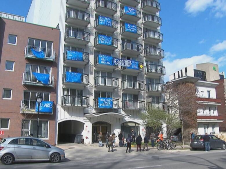 a 14-story building with blue banners on the balconies protesting evictions