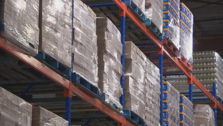 A pile of boxes on shelves in a large warehouse. 