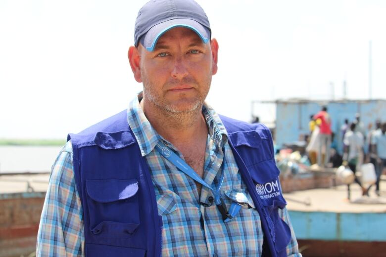 A man in a blue vest looks at the camera.