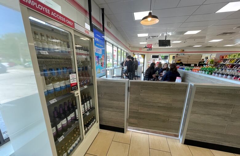 Inside a 7-Eleven store, fridge with beer and wine and sign saying 