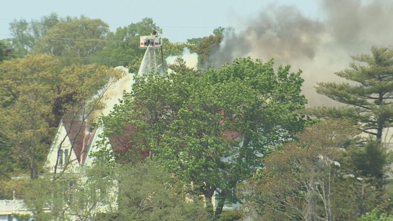 A firefighter holds a hose over the fire at the Waegwoltic Club.