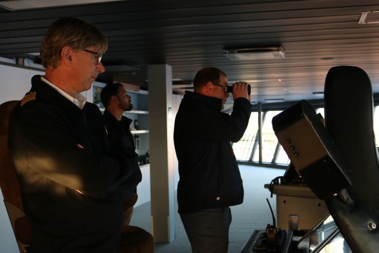 The pilot of the Oasis of the Seas looks on seriously as pilot Ryan McLean looks through a set of binoculars. 