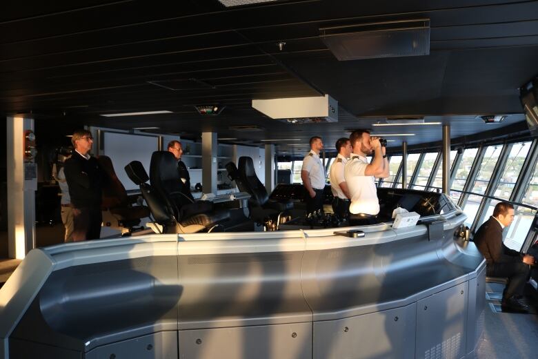 The crew of the Oasis of the Seas in sharp white shirts and navy trousers, surveying the approach to the Saint John Harbour. 